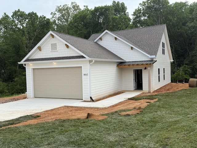 view of front of home with concrete driveway, a shingled roof, a front yard, and a garage