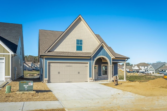 view of front facade with driveway, an attached garage, and roof with shingles