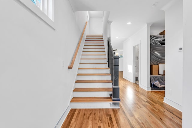 stairway with ornamental molding, recessed lighting, baseboards, and wood finished floors