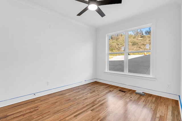 empty room featuring ceiling fan, visible vents, and wood finished floors