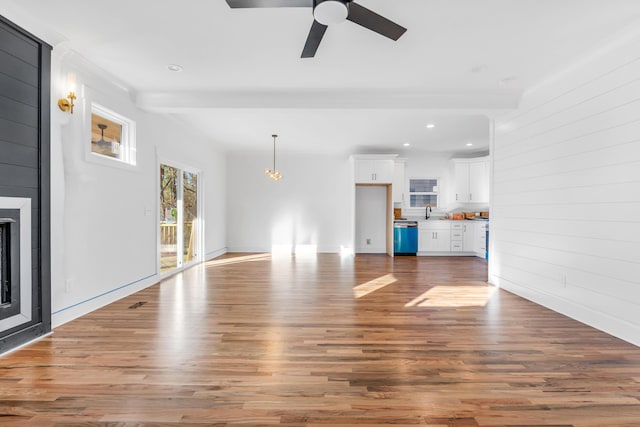 unfurnished living room with a sink, a fireplace, wood finished floors, and beam ceiling