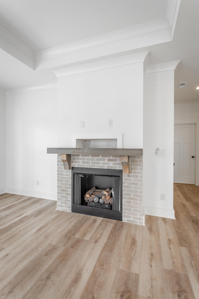 unfurnished living room featuring visible vents, a fireplace, ornamental molding, and wood finished floors