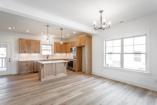 kitchen featuring a sink, light countertops, appliances with stainless steel finishes, light wood-type flooring, and tasteful backsplash