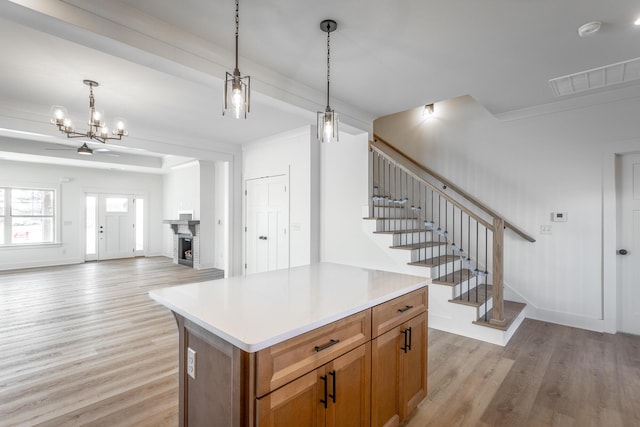 kitchen featuring light wood finished floors, visible vents, brown cabinets, open floor plan, and hanging light fixtures