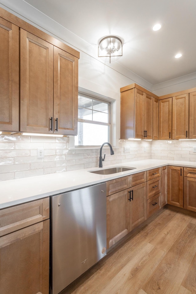 kitchen featuring light countertops, backsplash, light wood-style floors, a sink, and dishwasher