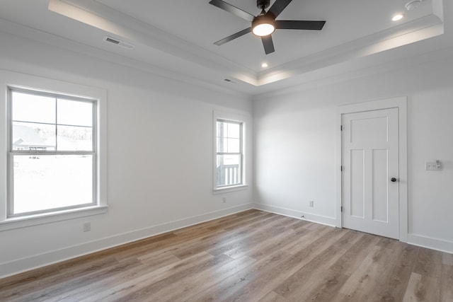 unfurnished room featuring light wood-style floors, a tray ceiling, baseboards, and recessed lighting