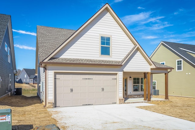 view of front of property featuring a garage, central AC, a shingled roof, and concrete driveway