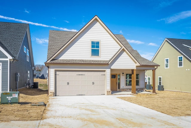 view of front of home featuring a shingled roof, concrete driveway, a garage, and central air condition unit