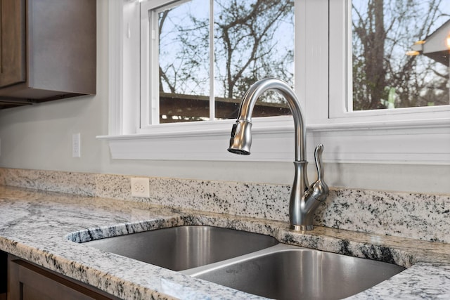 room details with dark brown cabinets, light stone counters, and a sink