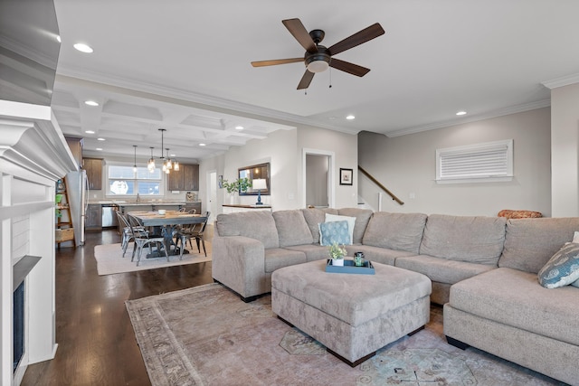 living room featuring recessed lighting, coffered ceiling, ornamental molding, dark wood-type flooring, and ceiling fan with notable chandelier