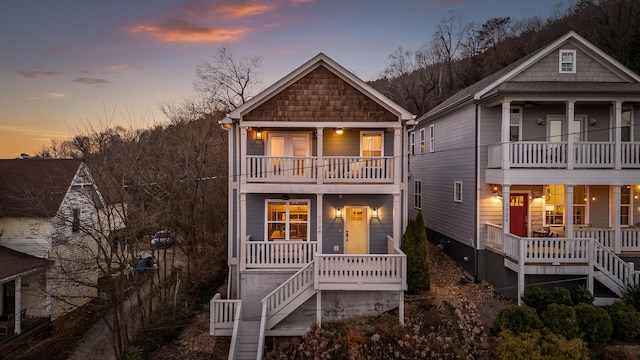 view of front of house featuring covered porch, stairs, and a balcony