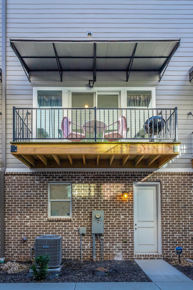 exterior space with brick siding, a balcony, and central air condition unit