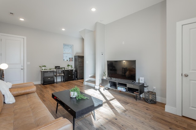 living area with baseboards, wood finished floors, and recessed lighting