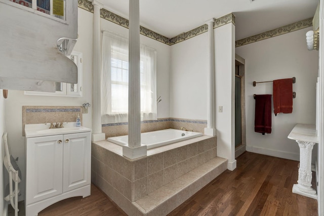 full bath with baseboards, vanity, a bath, and wood finished floors