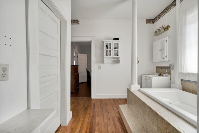 full bathroom with a garden tub, baseboards, and wood finished floors