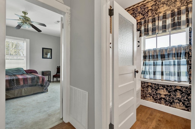 corridor featuring baseboards, visible vents, and wood finished floors