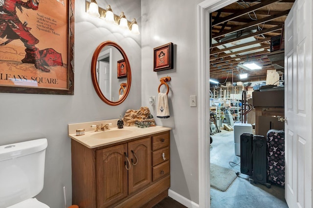 half bathroom with toilet, concrete floors, baseboards, and vanity