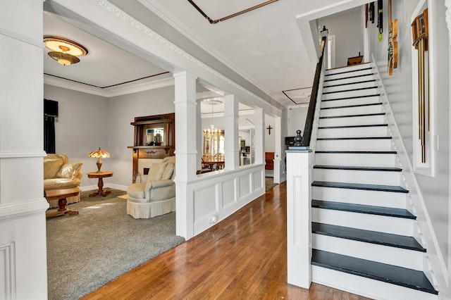 interior space featuring decorative columns, ornamental molding, and wood finished floors