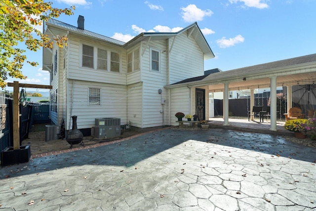 rear view of property featuring a chimney, fence, central AC, and a patio