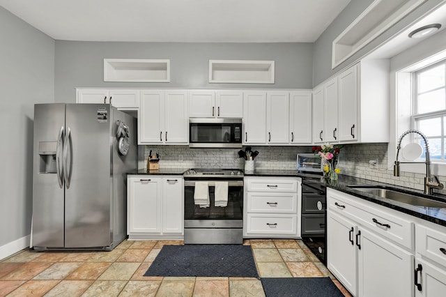 kitchen with stainless steel appliances, backsplash, a sink, and white cabinetry