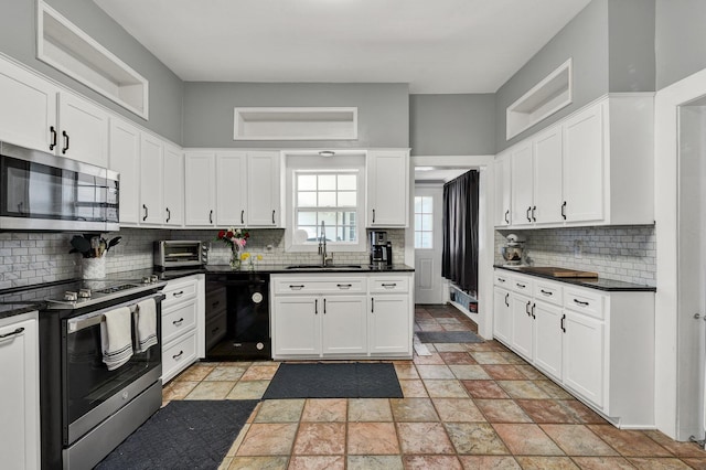 kitchen with stainless steel appliances, dark countertops, white cabinets, and a sink