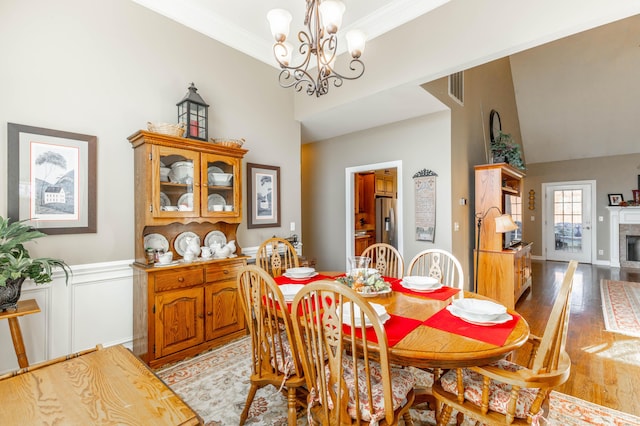 dining room with visible vents, crown molding, light wood-type flooring, a fireplace, and a notable chandelier