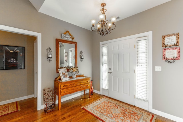 entryway with a notable chandelier, wood finished floors, and baseboards