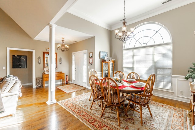 dining space with a chandelier, ornamental molding, light wood-style flooring, and ornate columns