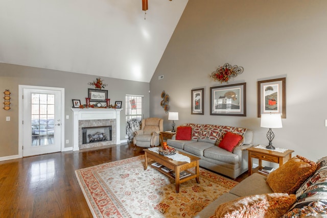 living area with a tile fireplace, high vaulted ceiling, a wealth of natural light, and wood finished floors