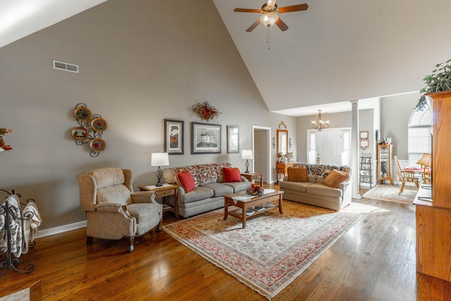 living room with high vaulted ceiling, ceiling fan with notable chandelier, wood finished floors, visible vents, and decorative columns