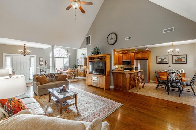 living area with ceiling fan with notable chandelier, visible vents, and wood finished floors