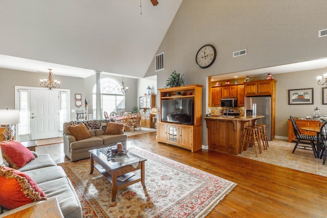 living room with light wood finished floors, decorative columns, and visible vents