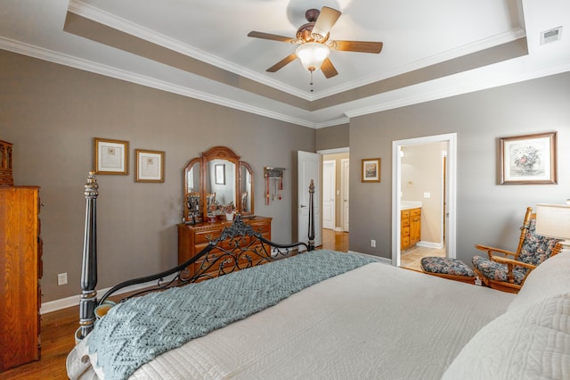 bedroom featuring baseboards, visible vents, a raised ceiling, wood finished floors, and crown molding