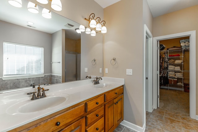 bathroom with double vanity, an enclosed shower, a sink, and visible vents