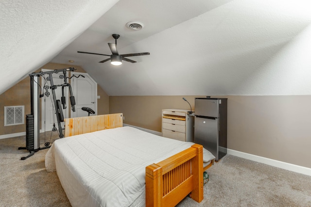 bedroom featuring visible vents, freestanding refrigerator, and light colored carpet