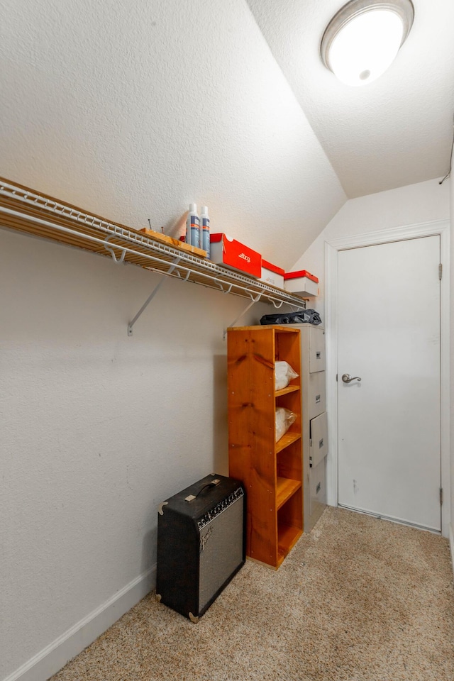 walk in closet with vaulted ceiling and carpet flooring