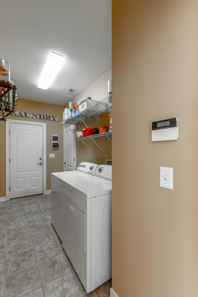 clothes washing area featuring washer and dryer, laundry area, a textured ceiling, and baseboards