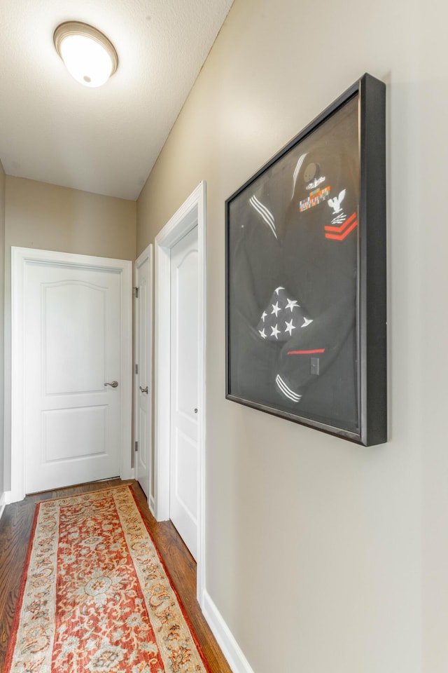 hall with baseboards and wood finished floors