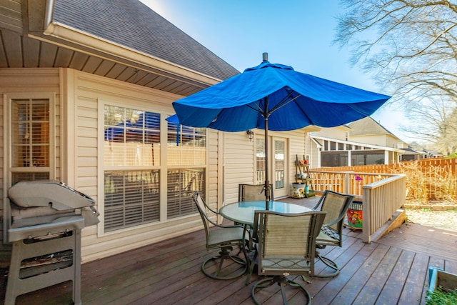 deck featuring outdoor dining space, fence, and a grill