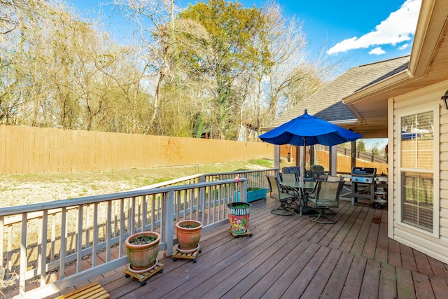 deck featuring outdoor dining space, fence, and grilling area