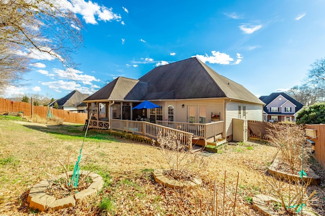 back of property featuring a shingled roof, a fenced backyard, a lawn, and a deck