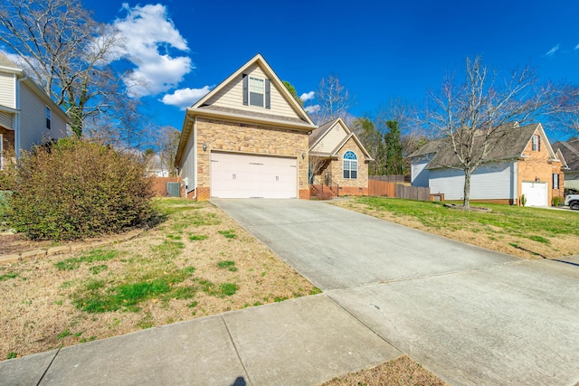 view of front facade featuring a garage, fence, driveway, stone siding, and a front yard