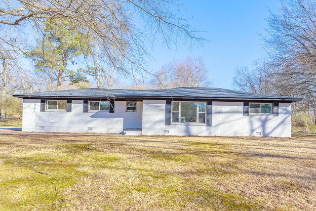 back of house with crawl space, brick siding, a lawn, and roof with shingles