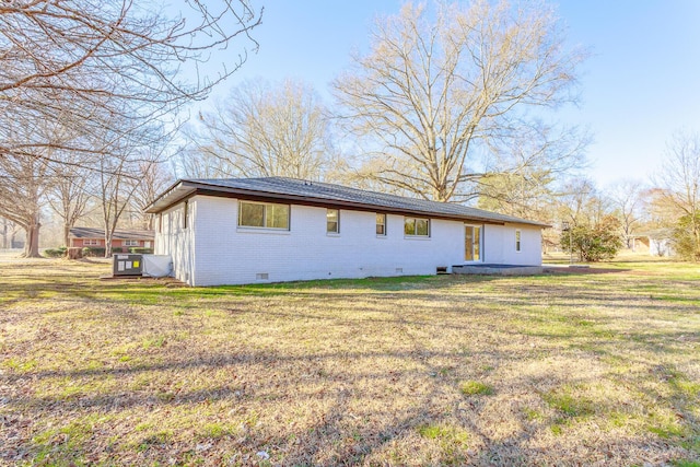 rear view of house with crawl space, brick siding, and a yard