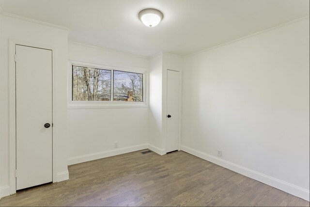 unfurnished bedroom with crown molding, baseboards, and wood finished floors