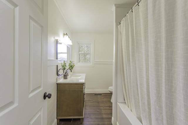 bathroom featuring toilet, a wainscoted wall, wood finished floors, vanity, and ornamental molding