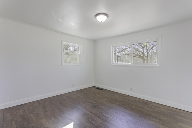 spare room featuring dark wood-style floors, visible vents, plenty of natural light, and baseboards