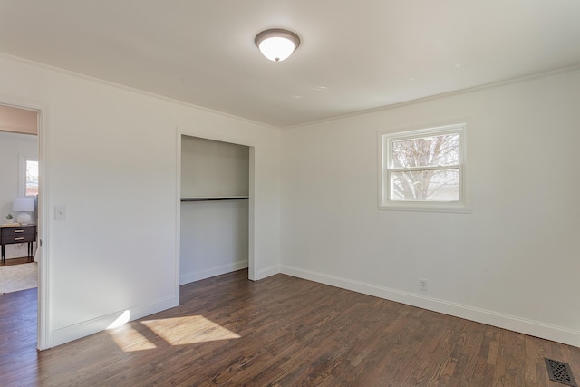 unfurnished bedroom with crown molding, multiple windows, visible vents, and wood finished floors