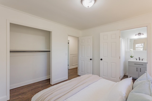 bedroom with a sink, wood finished floors, baseboards, a closet, and crown molding