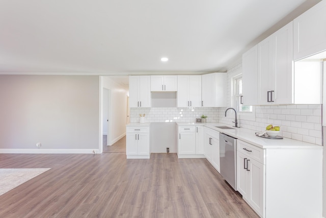 kitchen with light wood finished floors, tasteful backsplash, white cabinets, a sink, and stainless steel dishwasher